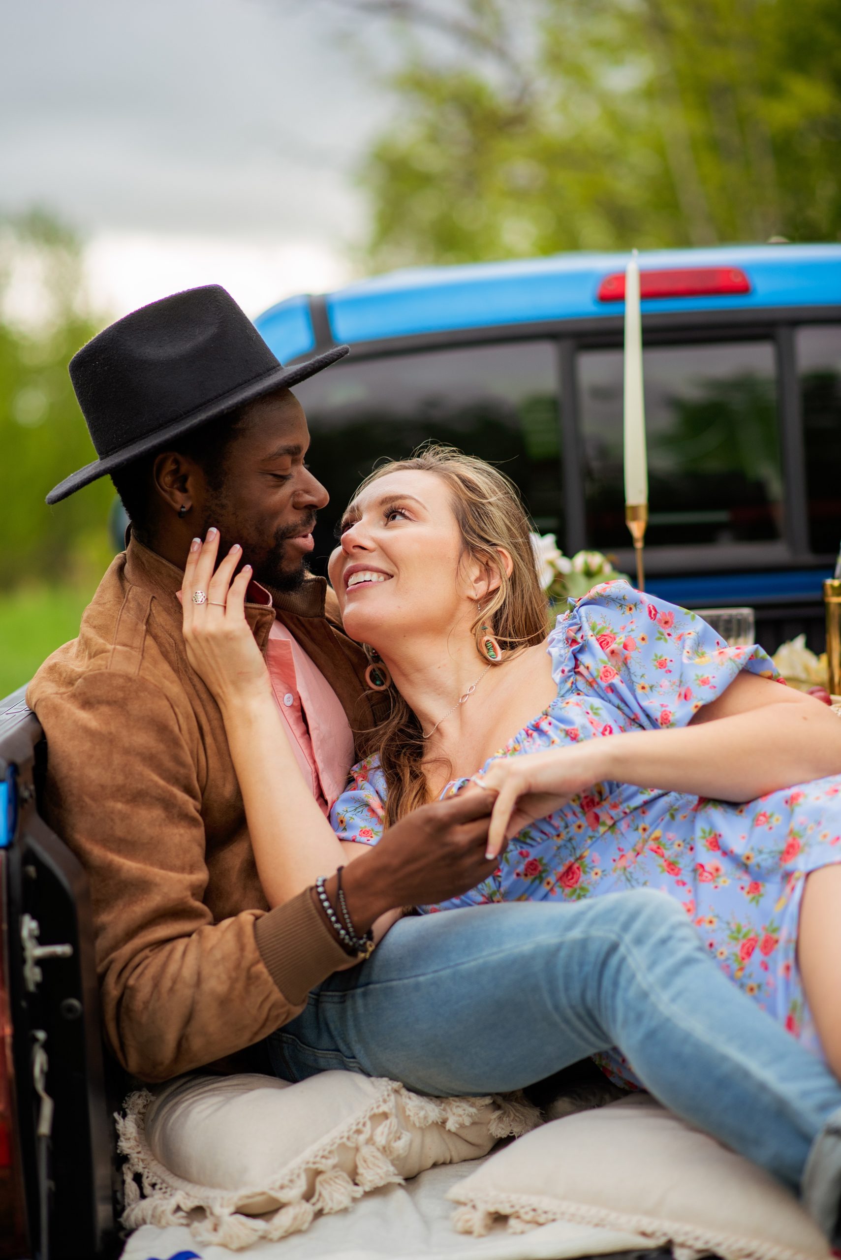 biracial couple leaning against each other in a blue pickup truck during their Edmonton engagement photography session